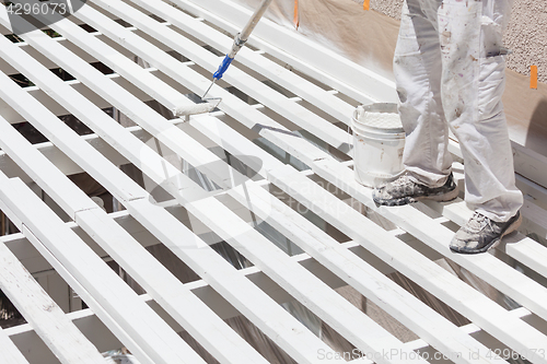 Image of Professional Painter Rolling White Paint Onto The Top of A Home 