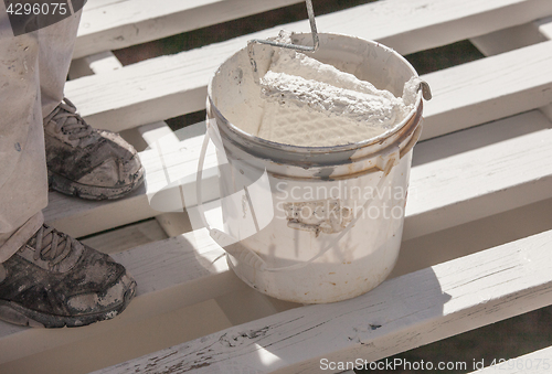 Image of Professional Painter Rolling White Paint Onto The Top of A Home 