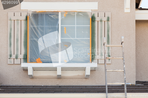 Image of Construction Ladder Leaning Up Against A House Being Painted