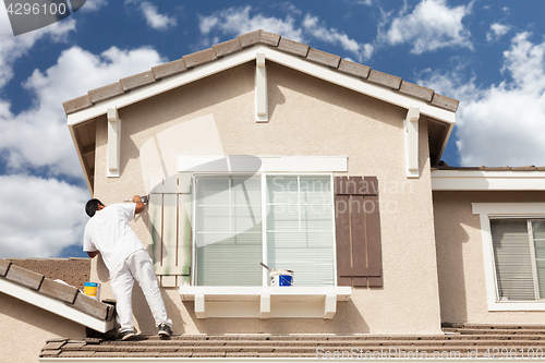 Image of Professional House Painter Painting the Trim And Shutters of A H