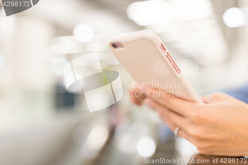 Image of Woman using cellphone in a station