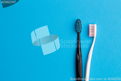 Image of Black, pink toothbrushes on blue