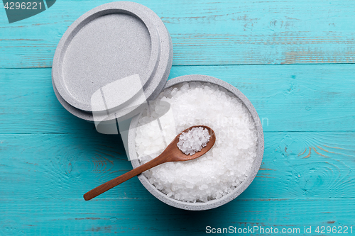 Image of Sea salt in an stone bowl with small wooden spoon on a blue wooden table