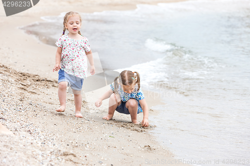 Image of Children on the sea beach. Twins going along sea water.