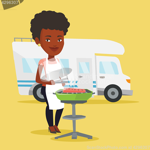 Image of Woman having barbecue in front of camper van.