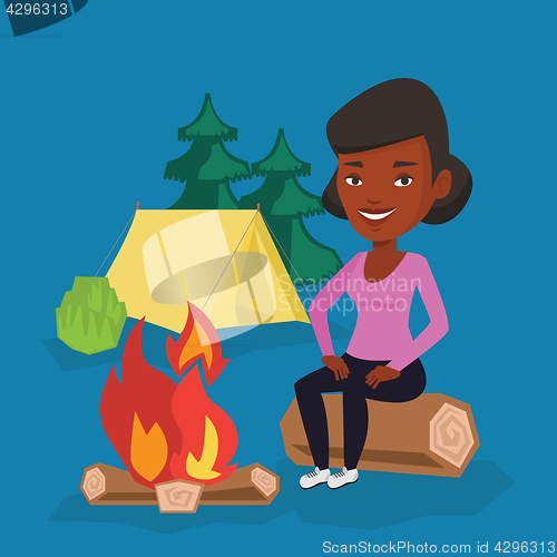 Image of Woman sitting on log near campfire in the camping.