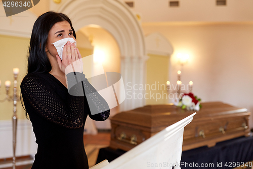 Image of woman with coffin crying at funeral in church