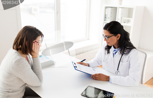 Image of doctor with clipboard and woman patient at clinic