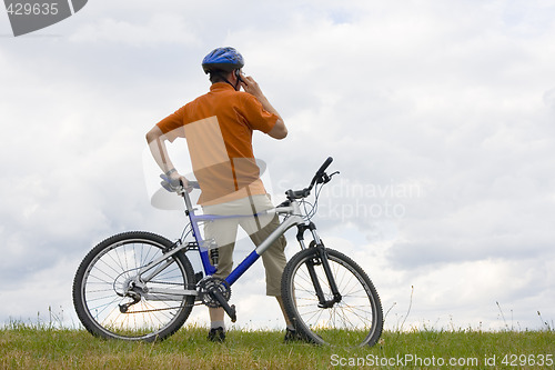 Image of Man with mountain bike talking on cell phone