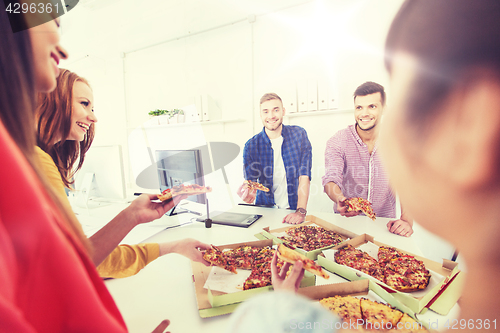 Image of happy business team eating pizza in office