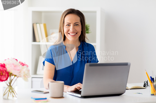 Image of happy woman with laptop working at home or office