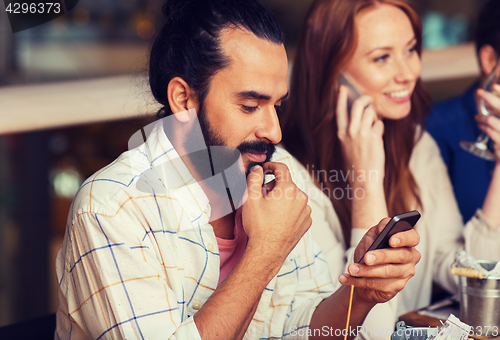 Image of happy friends with smartphones at restaurant