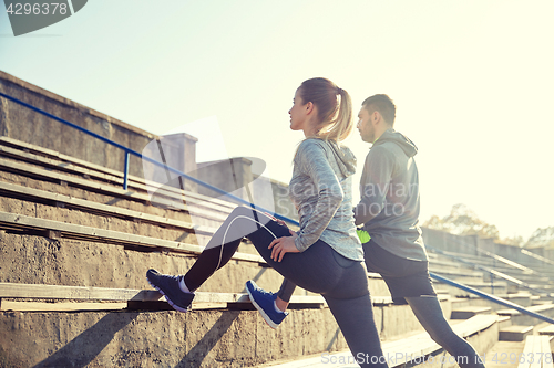 Image of couple stretching leg on stands of stadium