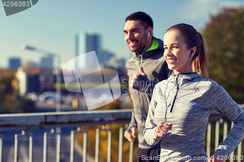Image of happy couple with earphones running in city