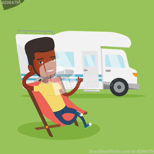 Image of Man sitting in chair in front of camper van.