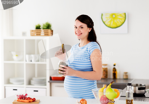 Image of pregnant woman eating pickles at home kitchen