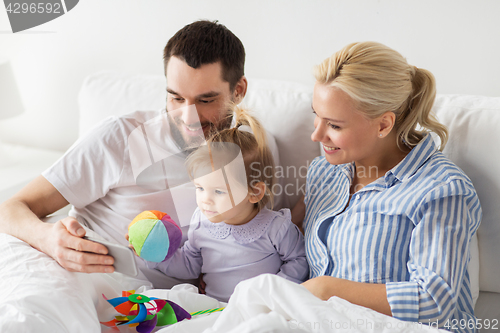 Image of happy family with smartphone in bed at home