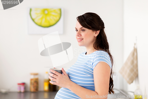 Image of happy pregnant woman with cup at home kitchen