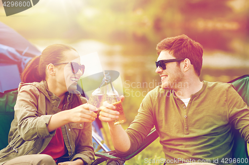 Image of happy couple clinking drinks at campsite tent