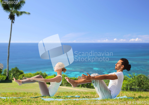 Image of couple making yoga half-boat pose outdoors