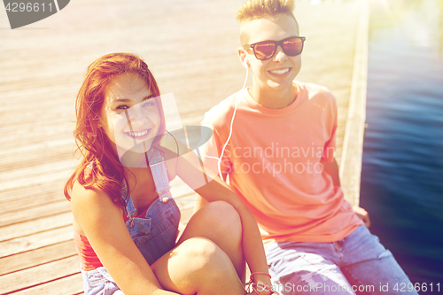 Image of happy teenage couple with earphones on river berth