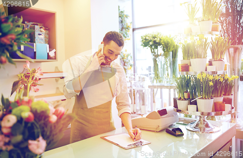 Image of man with smartphone making notes at flower shop