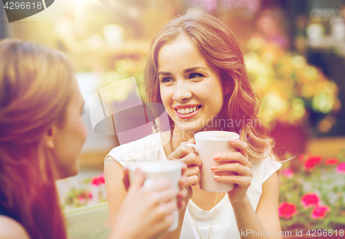 Image of smiling young women with coffee cups at cafe