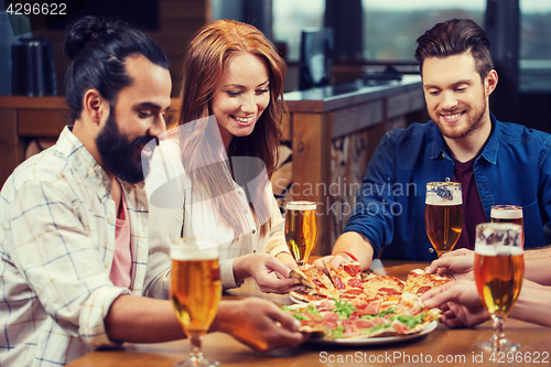 Image of friends eating pizza with beer at restaurant