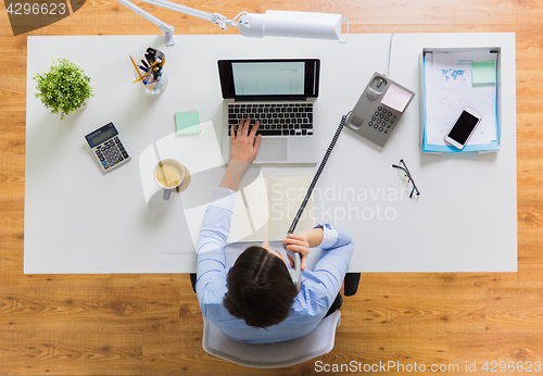 Image of businesswoman calling on phone at office table