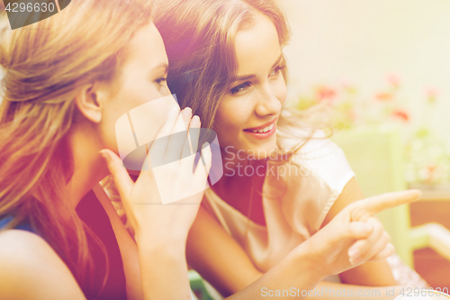 Image of smiling young women gossiping at outdoor cafe