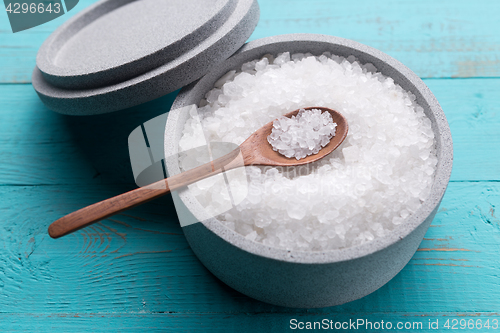 Image of Sea salt in an stone bowl with small wooden spoon on a blue wooden table