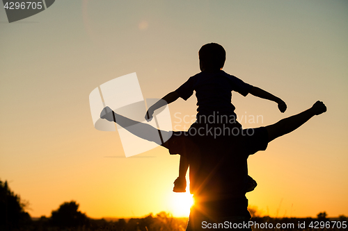 Image of Father and son playing in the park at the sunset time.