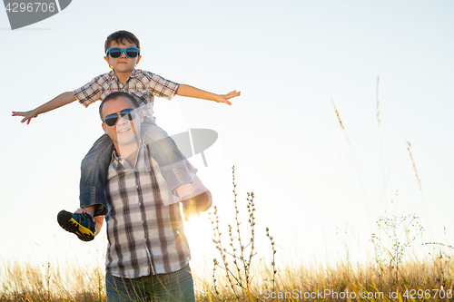 Image of Father and son playing on the field at the day time.