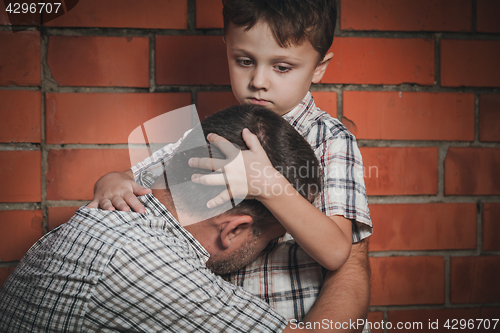 Image of Portrait of sad son hugging his dad