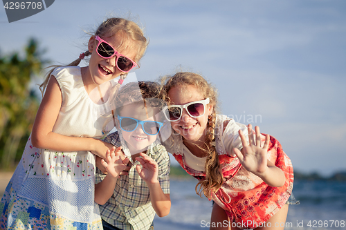 Image of Three happy children standing on the beach at the day time.