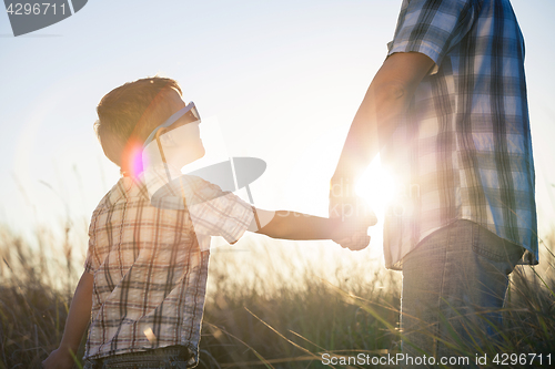 Image of Father and son playing on the field at the day time.