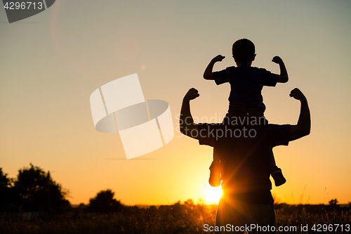 Image of Father and son playing in the park at the sunset time.