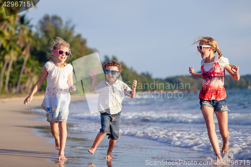 Image of Three happy children runing on the beach at the day time.