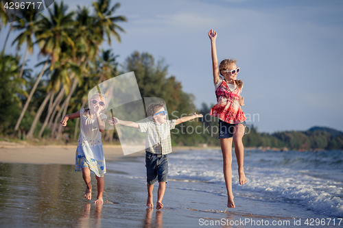 Image of Three happy children runing on the beach at the day time.