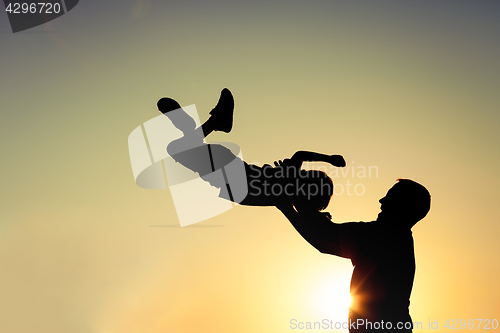 Image of Father and son playing in the park at the sunset time.