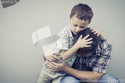 Image of sad son hugging his dad near wall