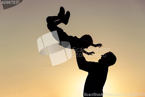 Image of Father and son playing in the park at the sunset time.