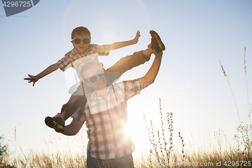 Image of Father and son playing on the field at the day time.