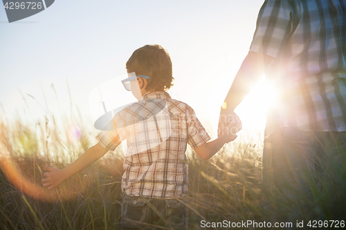 Image of Father and son playing on the field at the day time.