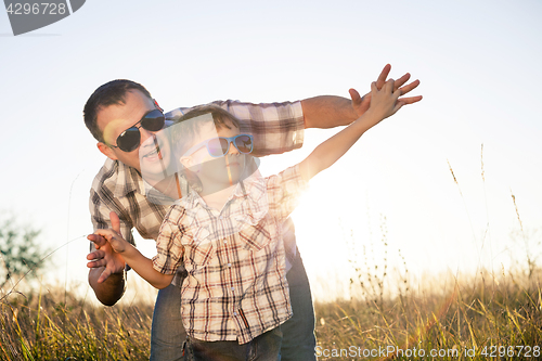 Image of Father and son playing on the field at the day time.