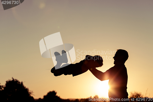 Image of Father and son playing in the park at the sunset time.