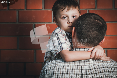 Image of Portrait of sad son hugging his dad