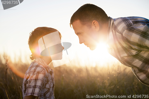 Image of Father and son playing on the field at the day time.