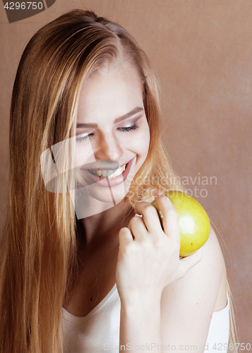Image of young pretty blond woman with green apple happy cheerful smiling
