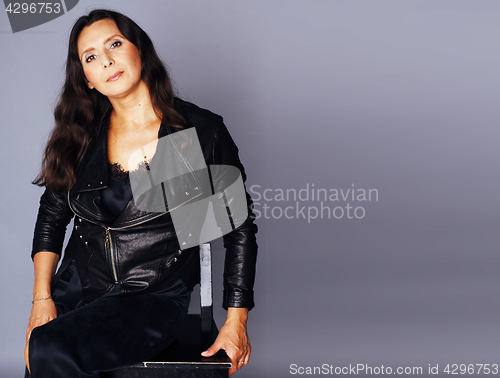 Image of pretty brunette confident mature woman sitting on chair in studi